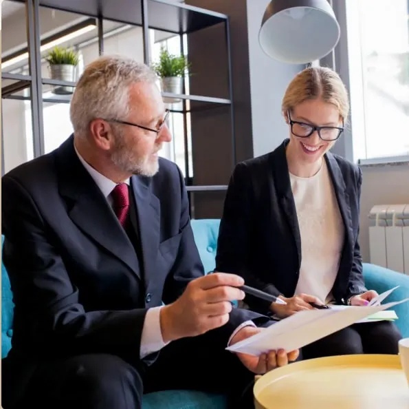 Two colleagues reviewing a document together in a meeting room.